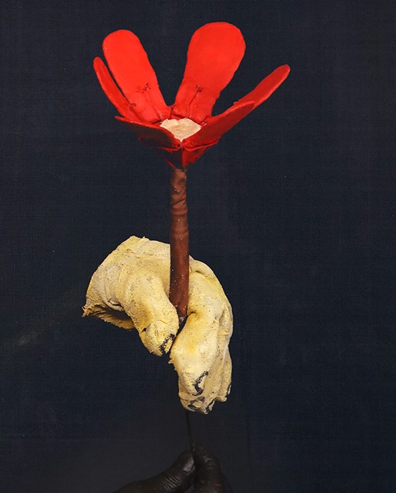 a mechanical hand holds a red mechanical flower